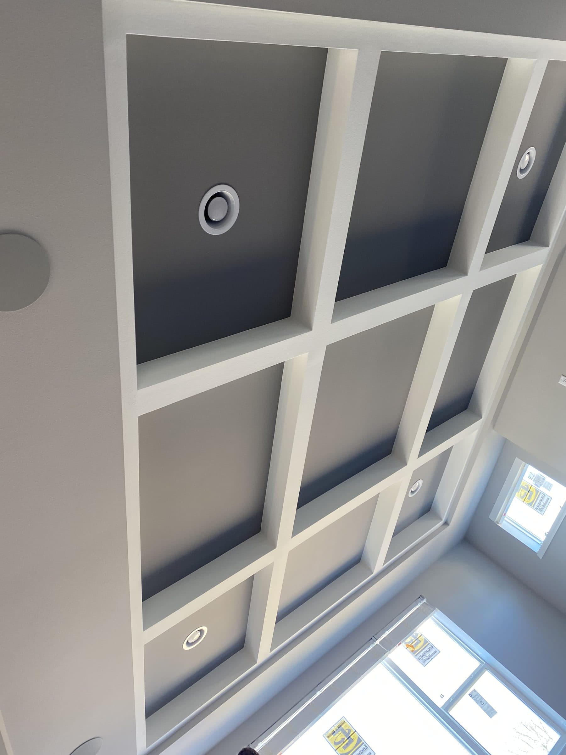 Coffered ceiling with gray recessed panels inside a white grid, lit by clerestory windows.