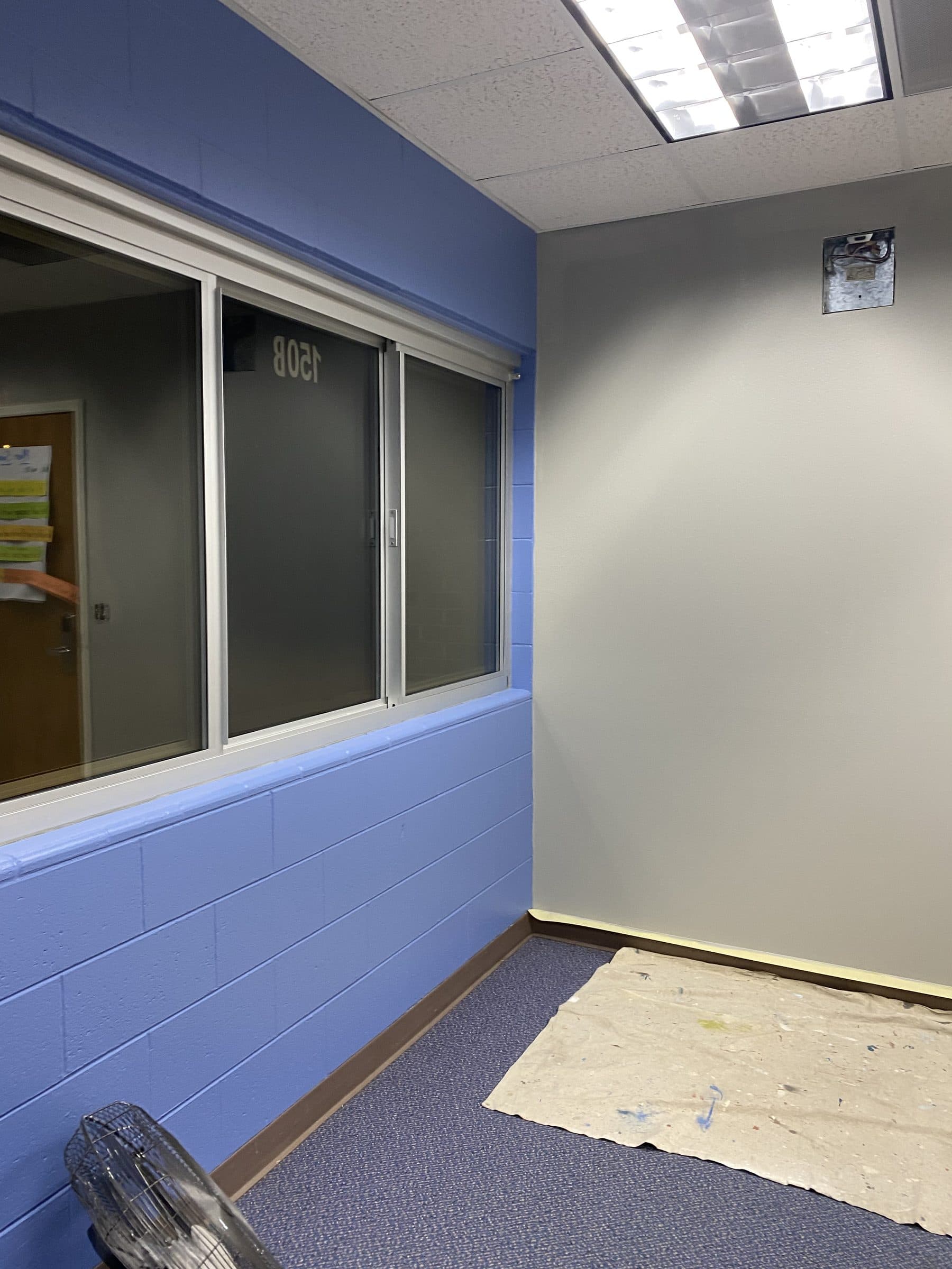Classroom wall painted in two tones, periwinkle blue on the block base and gray above the window band.