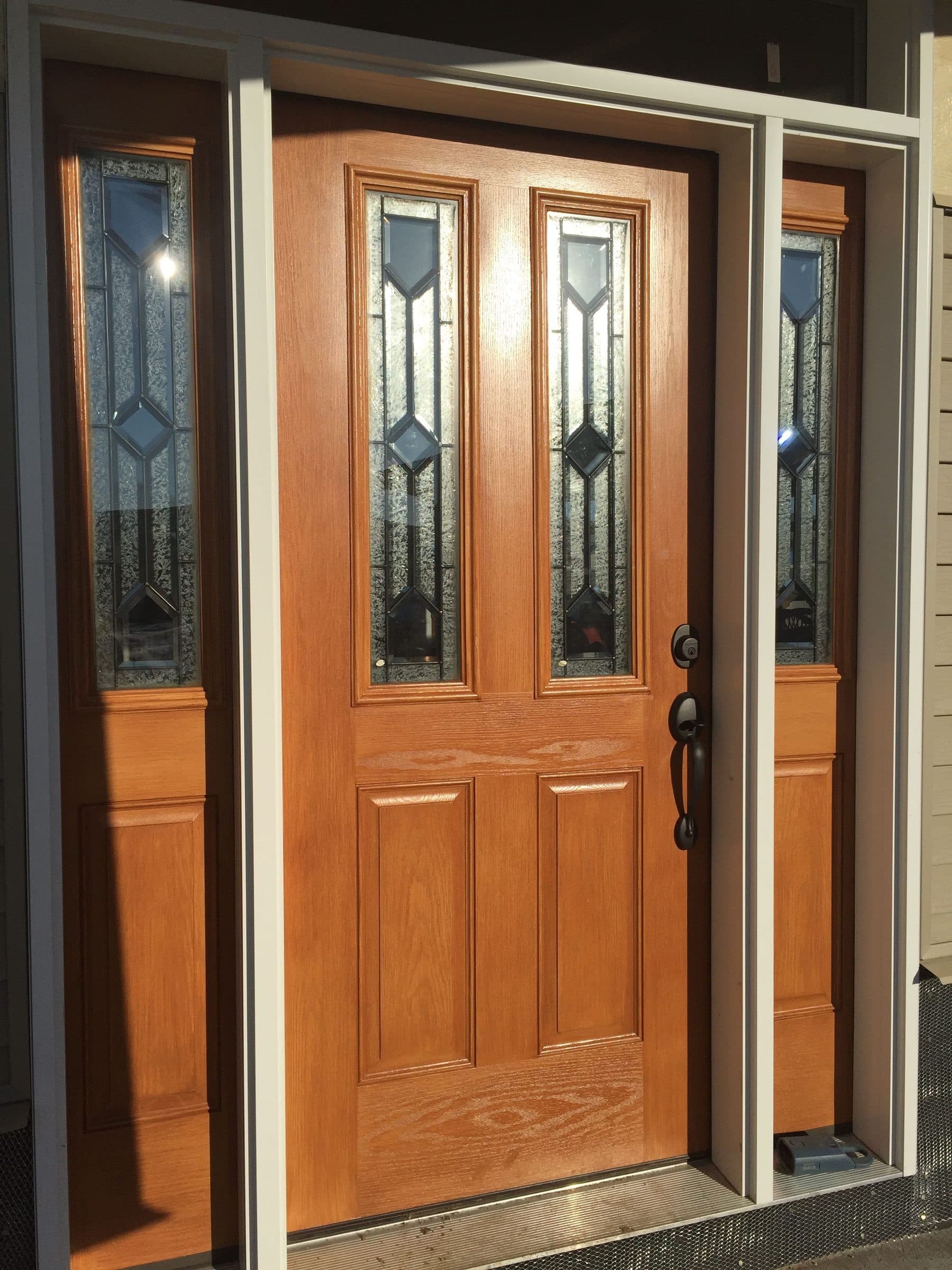 Closer view of the light oak entry door, showing the open grain raised by the stain alongside the beveled leaded glass.