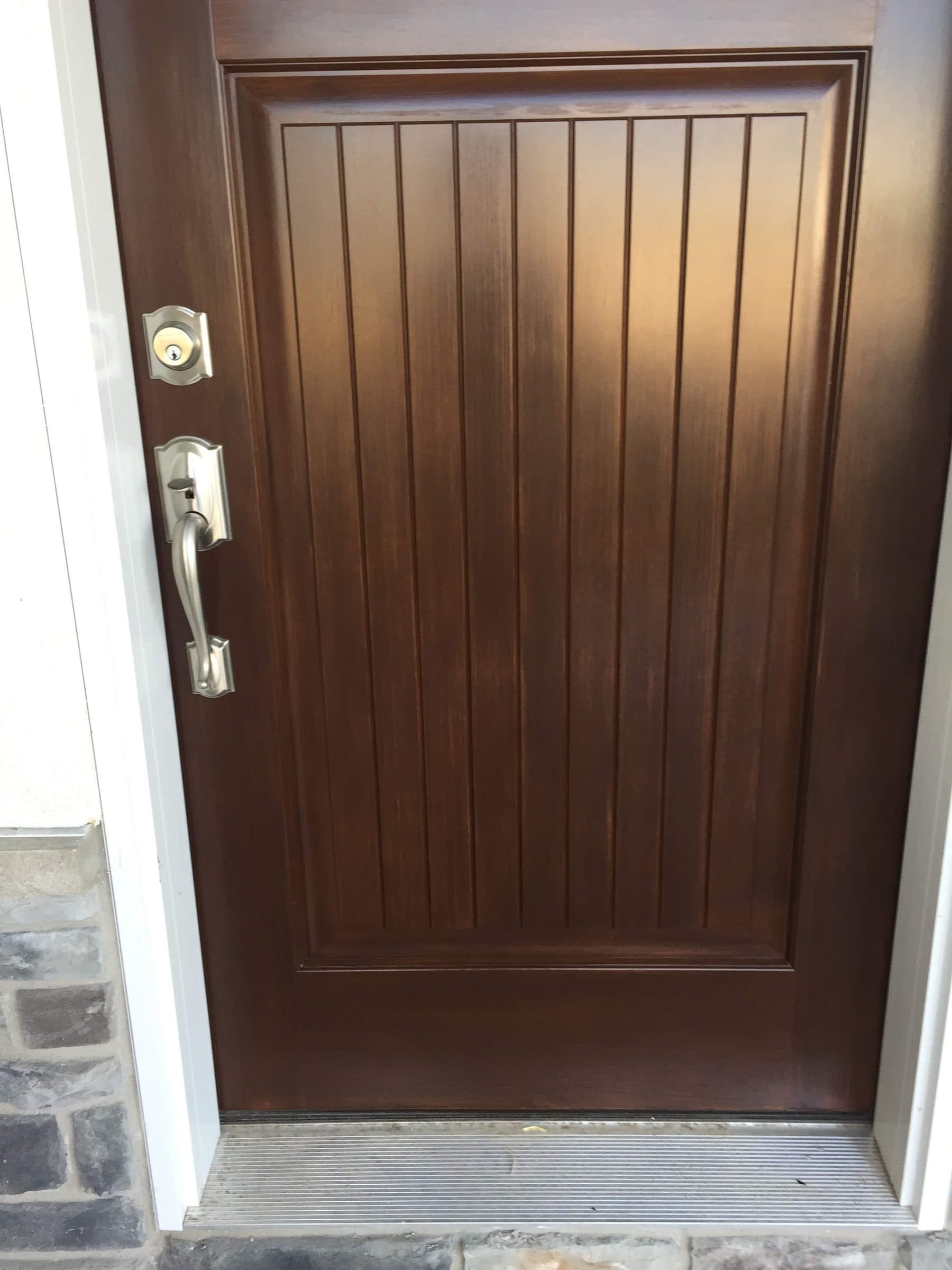 Close view of a stained vertical plank entry door with the handleset and deadbolt reinstalled after finishing.