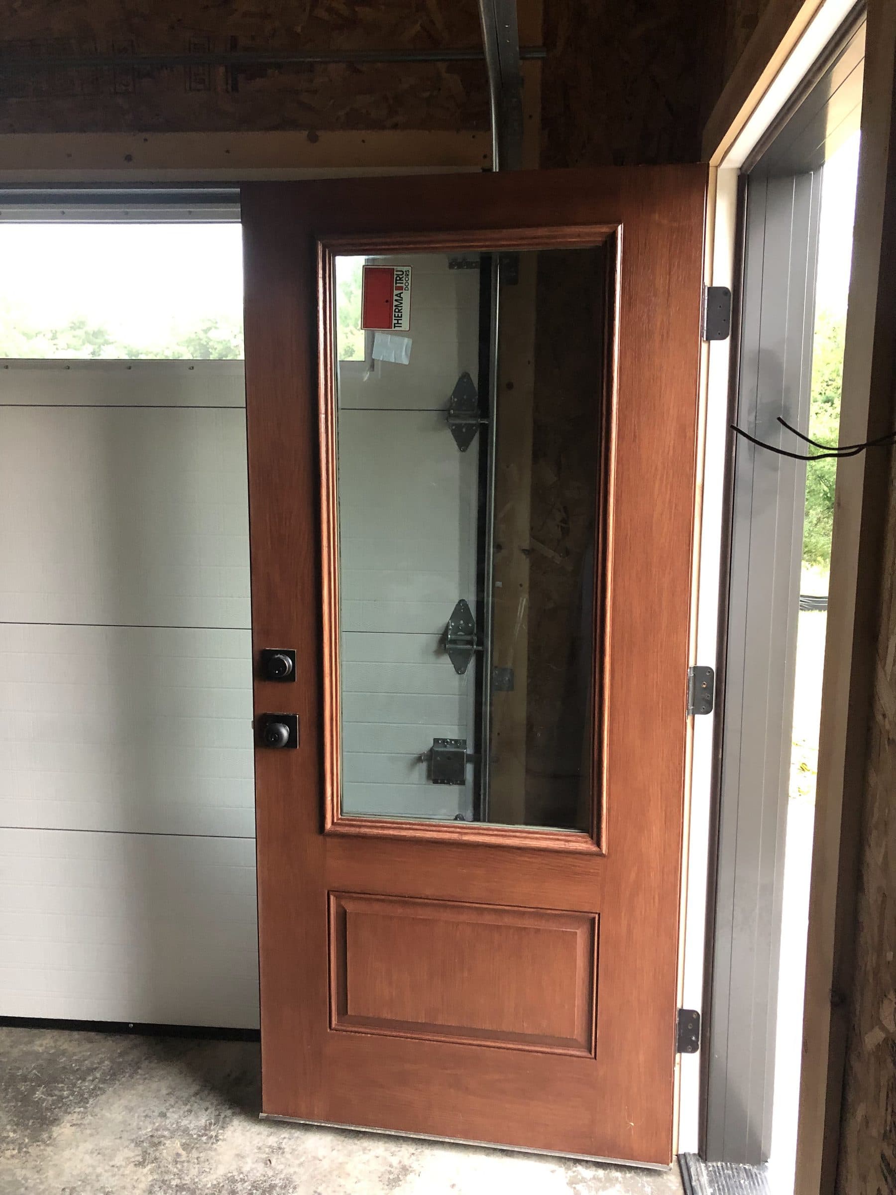 The stained side door seen from inside, standing open so the finish carried onto the hinge edge is visible.