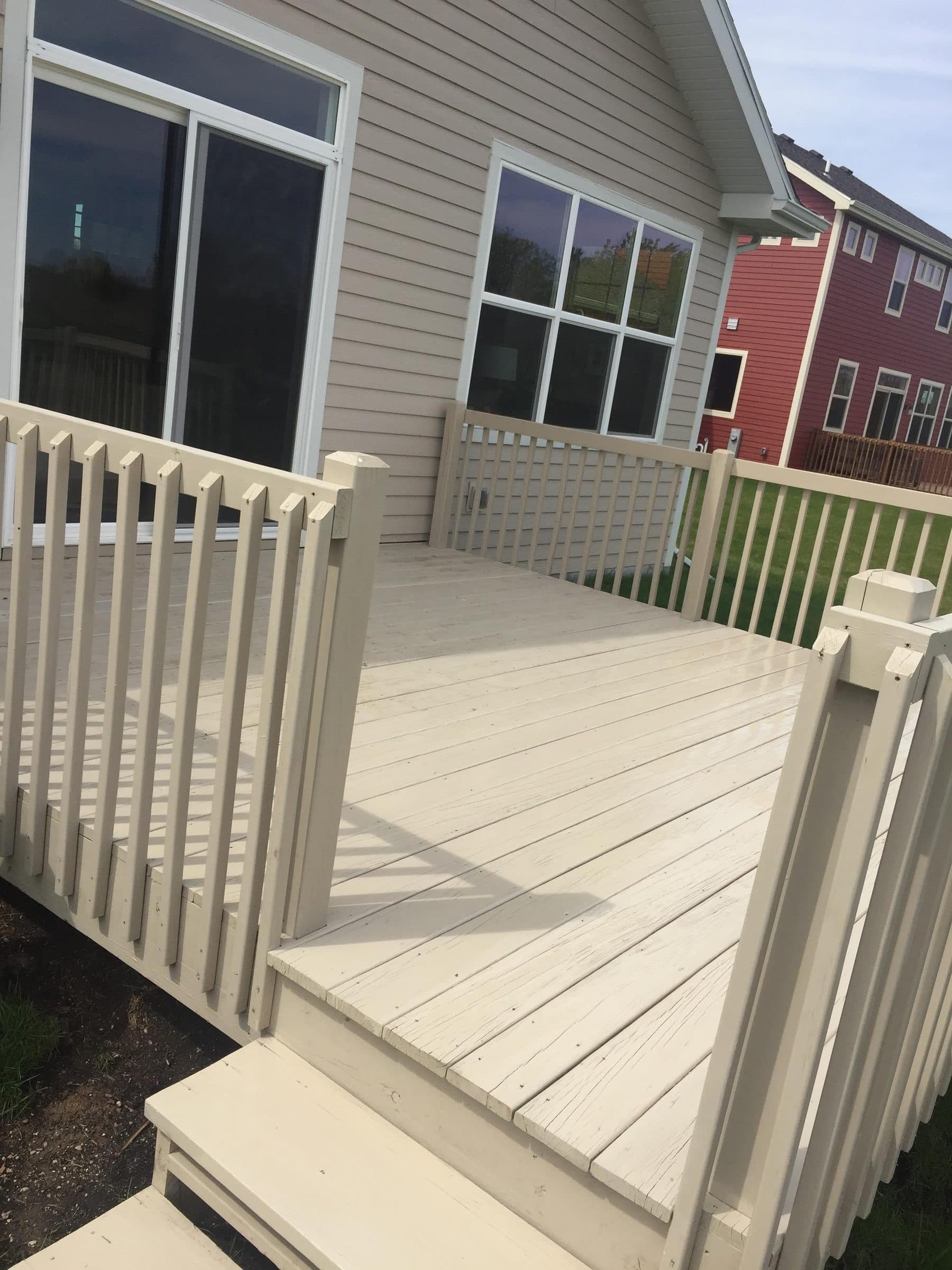 Cream-painted deck boards, steps and rail with a green lattice skirt, beside gray siding.