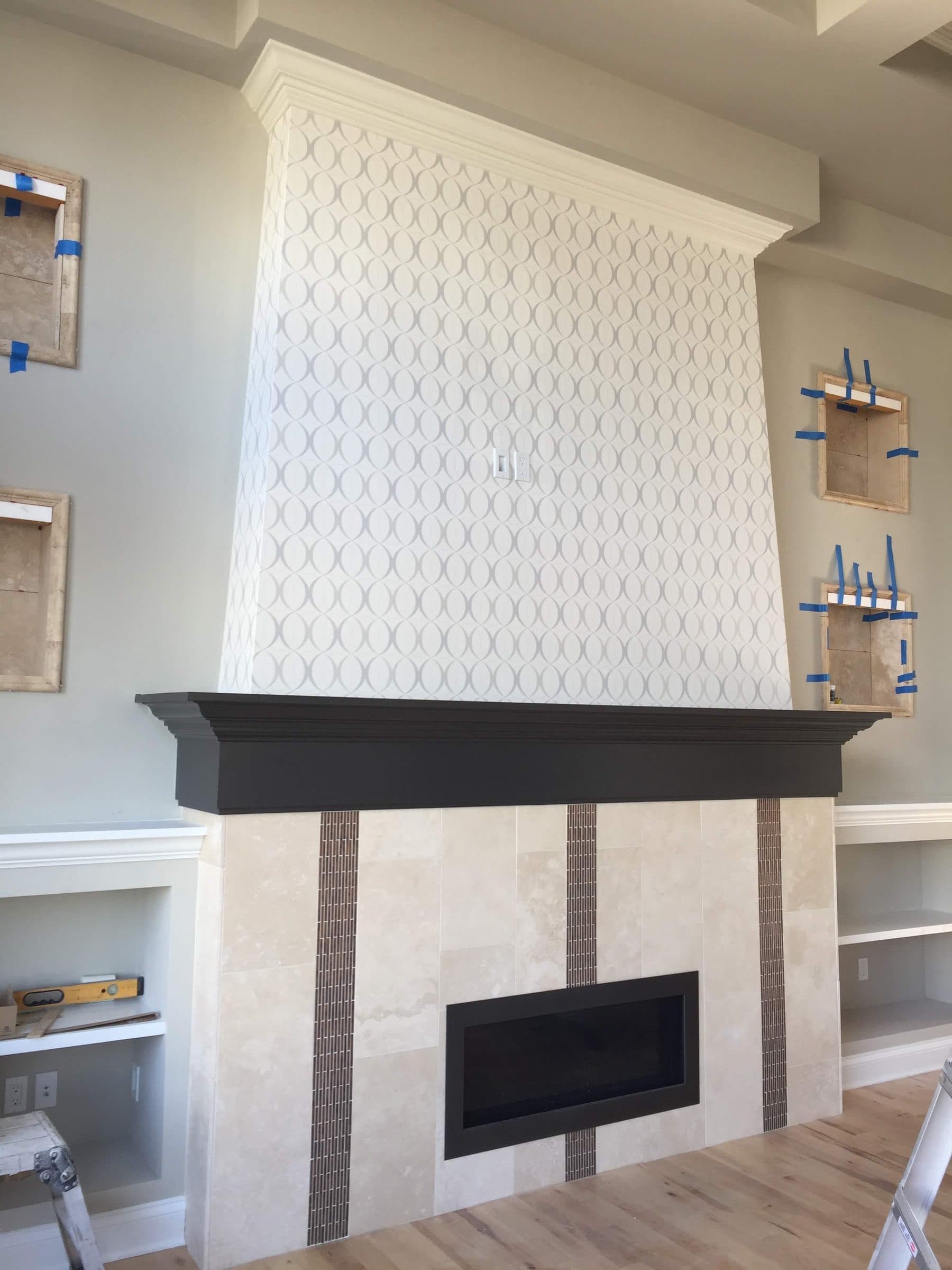 White painted fireplace surround with a patterned overmantel panel and a black-painted mantle shelf.