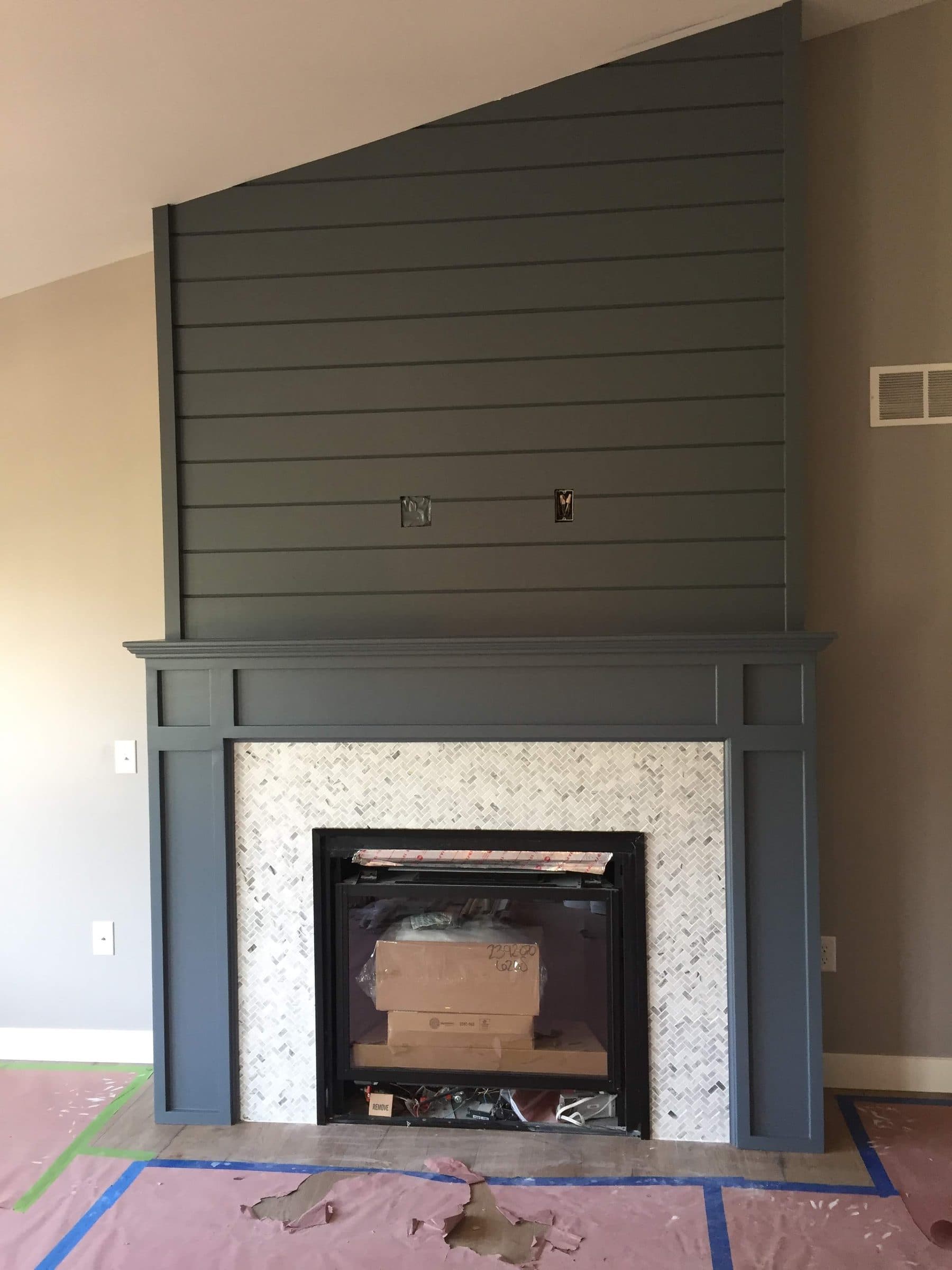 Fireplace surround clad in shiplap and painted deep blue-green, with a matching mantle above a stone hearth.