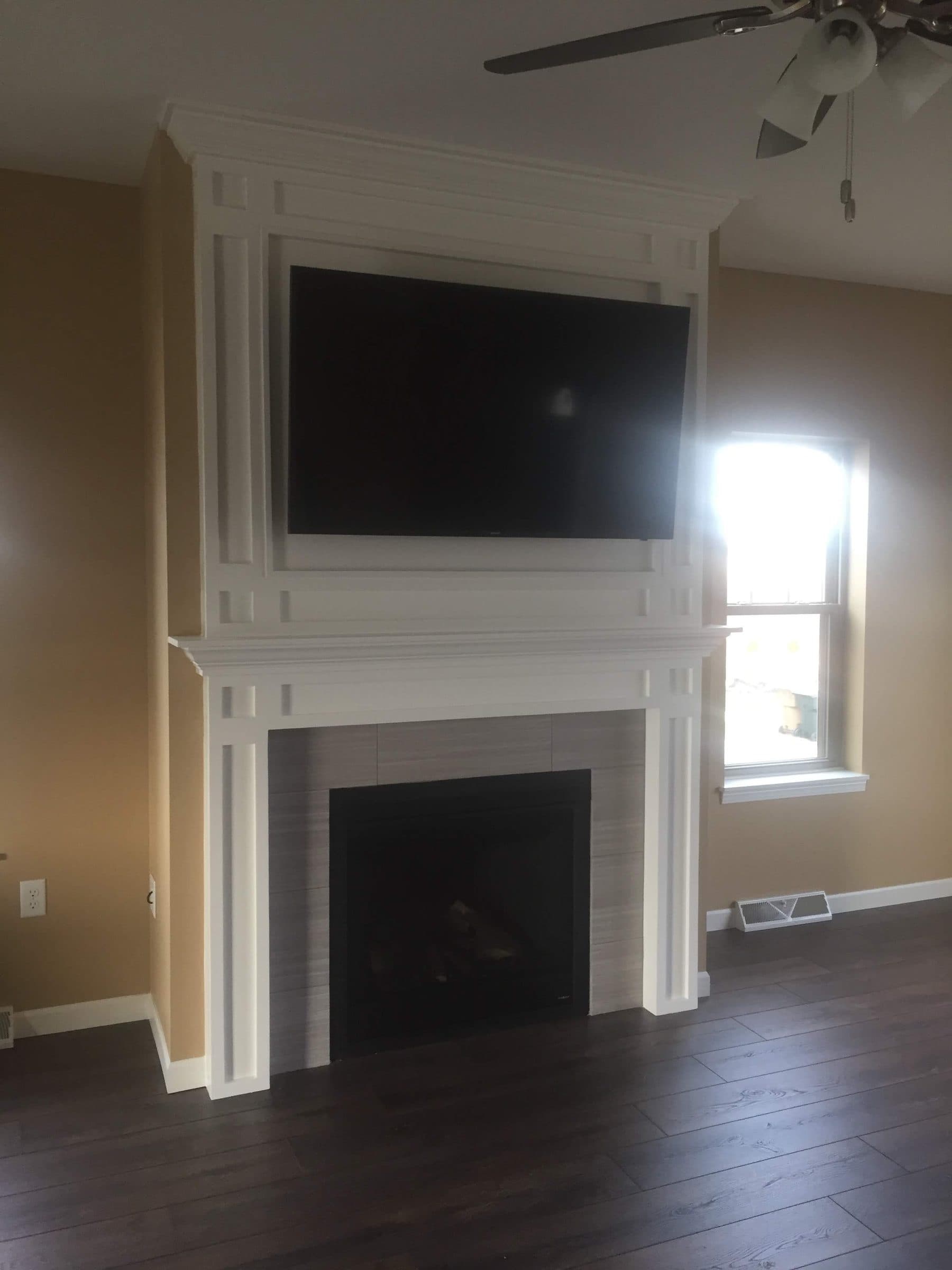 White fireplace surround and mantle finished, with the television reinstalled and the trim cut clean to the wall.