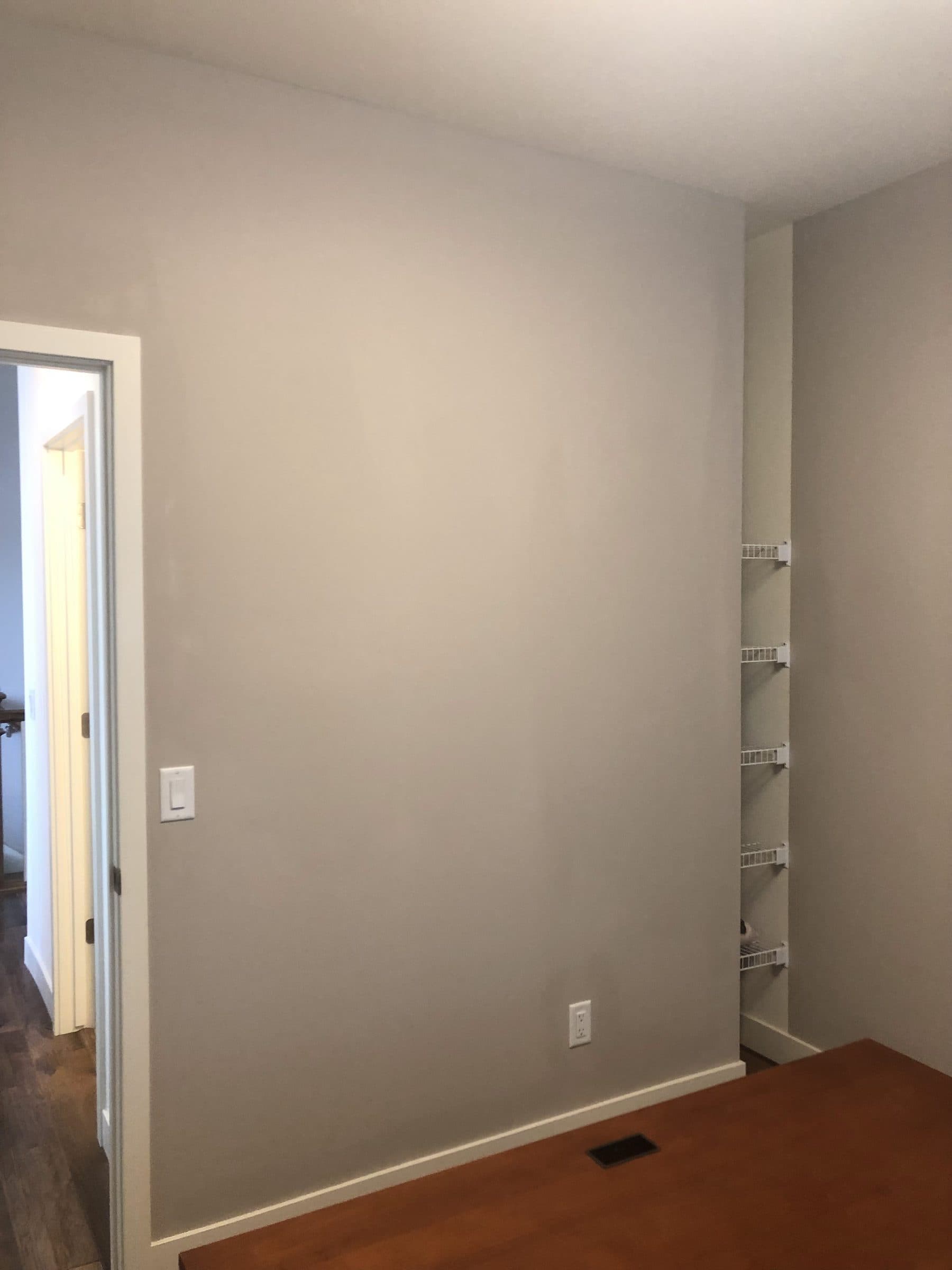 Empty room in a warm neutral gray with white baseboard and door casing, ready to hand back.
