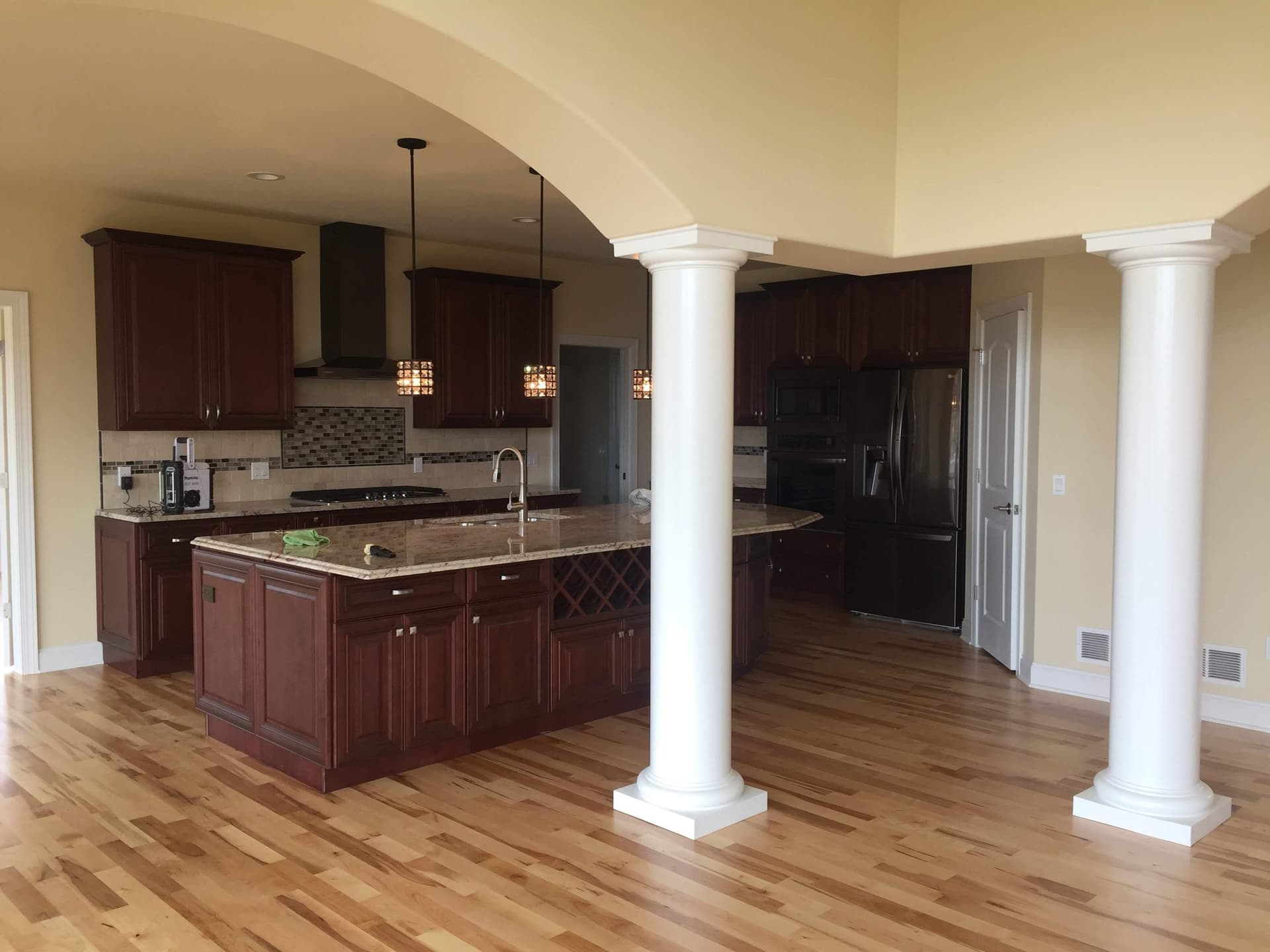 Two white painted columns framing the opening between a living room and a kitchen with dark stained cabinets.